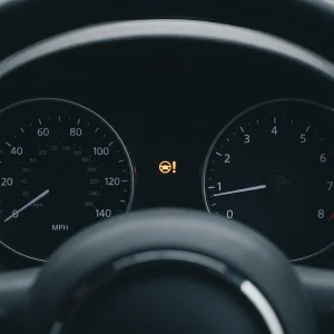 Amber electric power steering warning light illuminated on a car instrument cluster between the MPH speedometer and rev counter