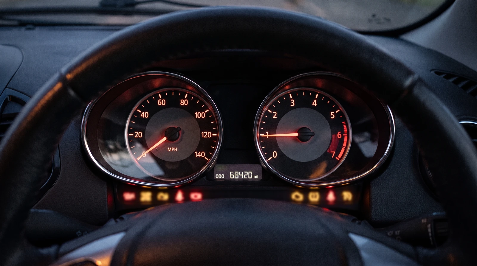 Ford Ka instrument cluster lit at night: twin dials with the speedometer reading to 140 MPH, the rev counter alongside, the odometer showing 68,420 miles, and a row of red and amber warning symbols illuminated across the bottom