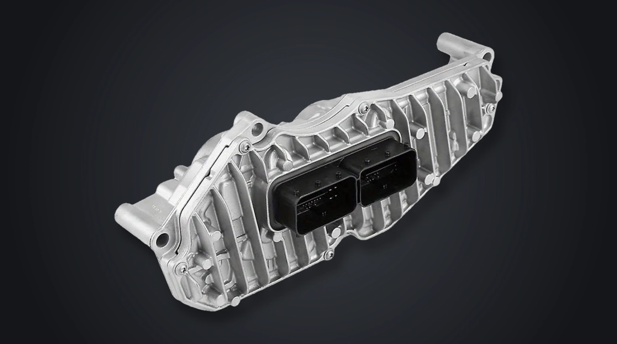 Close-up of a transmission control module's cast aluminium housing and electrical connector, the unit that reads sensor data and shifts an automatic gearbox